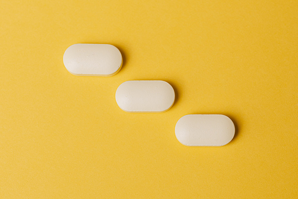 three white pills on a yellow background