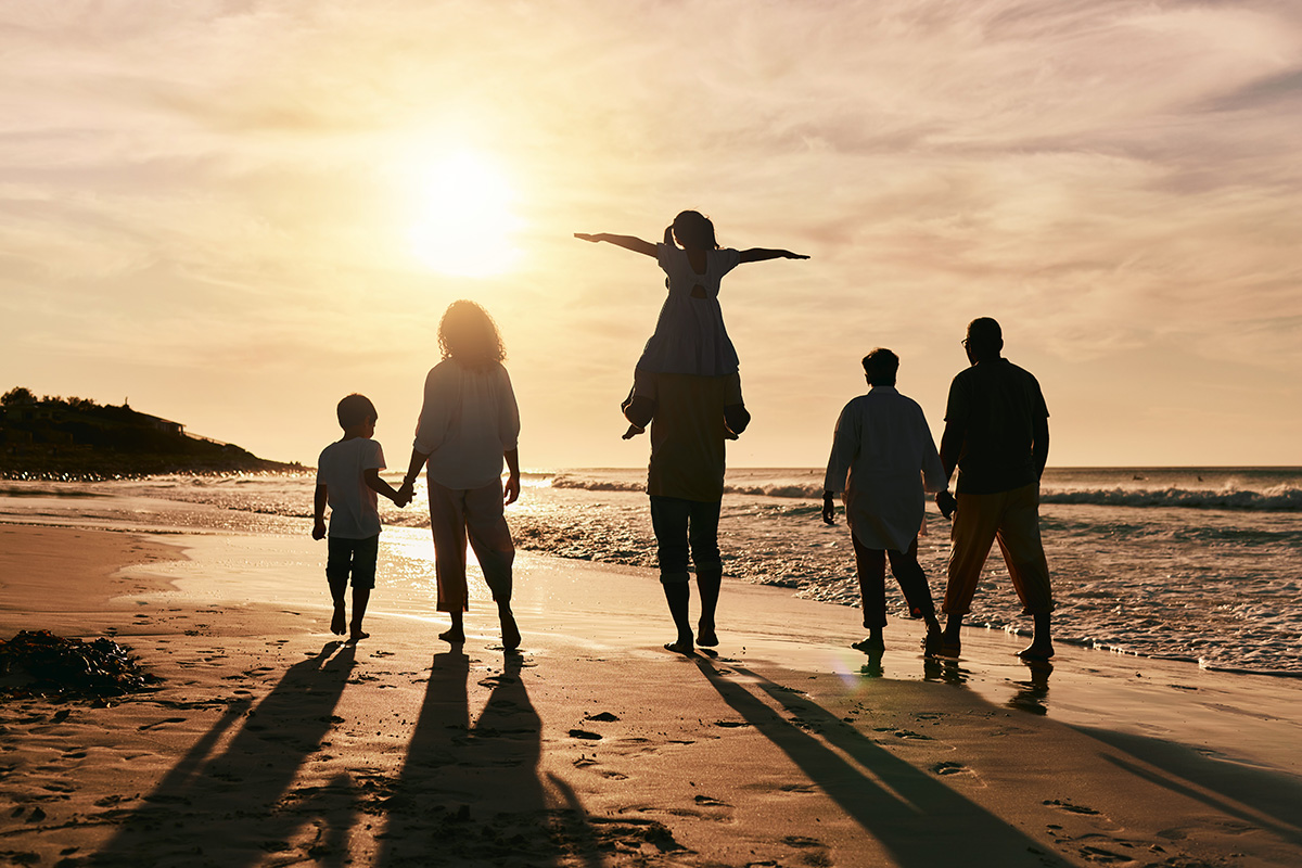 family walking on the beach at sunset